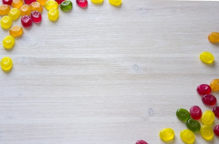 Colorful candy decoration frame over wooden white backgroundの写真素材