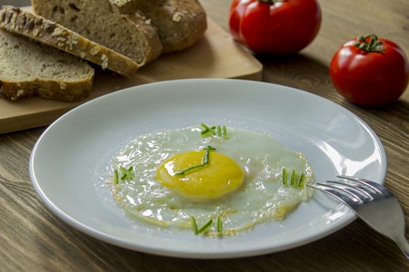 Breakfast: Fried egg in form of a clock, tomato and bread with fork
