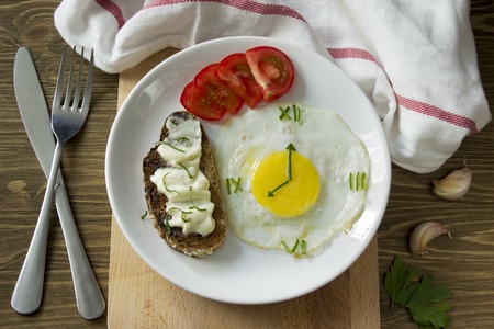 Breakfast: Fried egg in form of a clock, tomato and sandwich with fork and knife