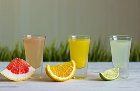 fresh citrus juices with fruits on a white background with grassの写真素材