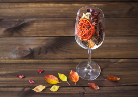 Autumn leaves in a wine glass on wooden table background. Seasonal, sunday relax and still life conceptの写真素材