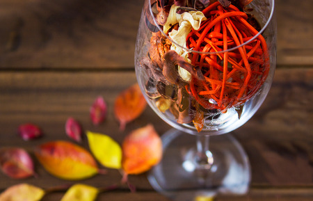 Autumn leaves in a wine glass on wooden table background. Seasonal, sunday relax and still life conceptの写真素材