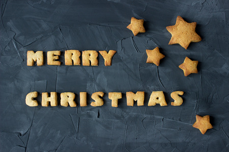 christmas background with baked gingerbread stars and words merry christmas on the concrete background. creative ideaの写真素材
