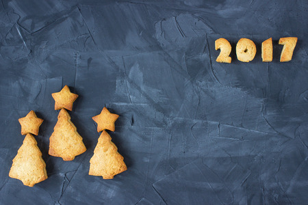 background with baked gingerbread in a form of christmas trees and text 2017 on the concrete...