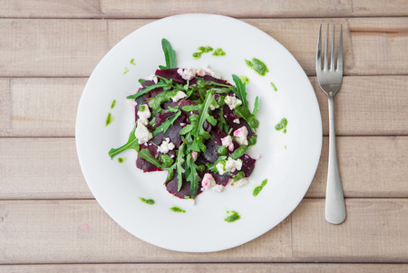 Salad with beet, feta, arugula and pesto with fork on light wooden table. horizontalの写真素材