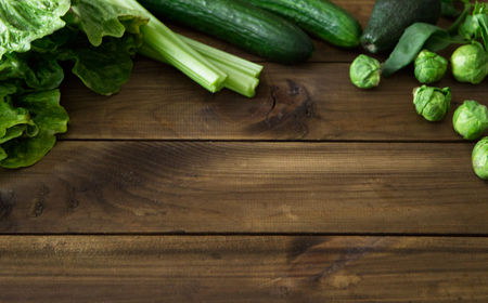 Products containing folic acid - B9 vitamin . Green vegetables on dark wooden background. Celery, avocado, Brussels sprouts, basil, cucumber romaine salad. space for textの写真素材