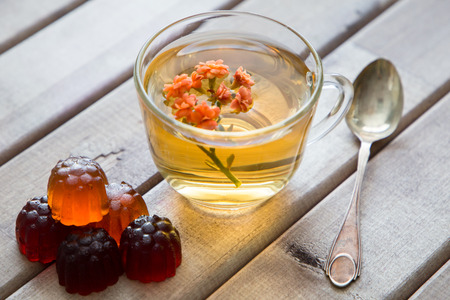 Closeup of cup of tea with bright flower on light wooden table with spoon and Marmalade. still life...