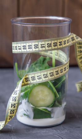 Blender full of vegetables and yogurt and meter. 90 60 90 concept on dsrk background. verticalの写真素材