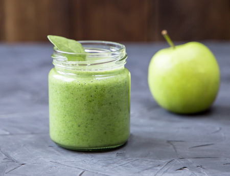 Healthy green smoothie with spinach in a jar and apple against dark backgroundの写真素材