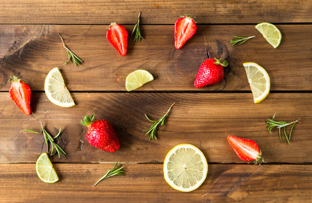 Fresh strawberries, lime slices and rosemary on old wooden background. top viewの写真素材