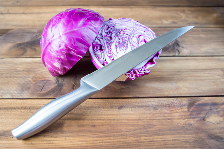 close up of a red cabbage on a wooden table with knife. space for textの写真素材