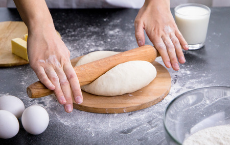 Making dough by female hands on wooden table background with ingredients
