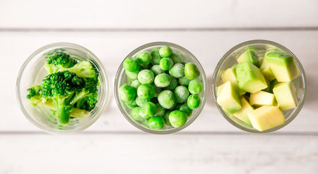 closeup of assortment of green cut vegetables in shot glass on white background. top viewの写真素材