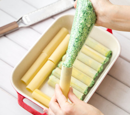 closeup of Spinach and cheese cannelloni preparation : Stuffing the cannelloni with the spinach and cheese fillingの写真素材