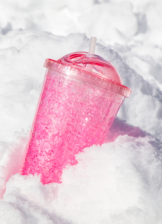 pink travel mug in snow. ice tumbler. verticalの写真素材