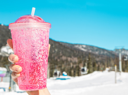 closeup pink travel mug in snow. ice tumbler against Cableway in the mountainsの写真素材