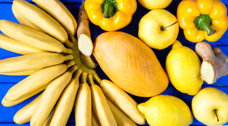 yellow fruits and vegetables isolated on a blue background. top viewの写真素材