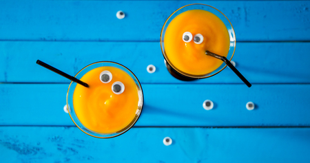 funny and scary cocktail for halloween in high martini glasses on blue tableの写真素材