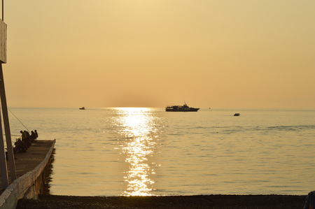 Sunset over the sea, pleasure boat and fishermen on the pierの写真素材