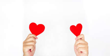Two hands holding red paper, heart-shaped, white backgroundの写真素材