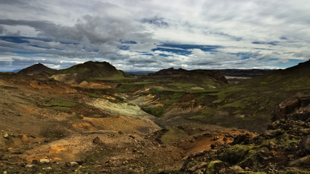 Valley with tiny ârainbow mountainsâ and green hills in the distance with volcanic soil around on hiking trail Reykjavegur in backcountry of Iceland. Reykjanes peninsula.の写真素材