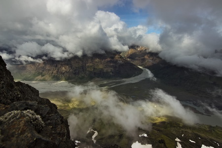 View from the top of the mountain over the valley with clouds above it in Skaftafell national park in Southern Iceland.の写真素材
