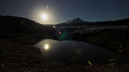 Small lake in foreground near Skalafellsjokull glacier during sunset with clear sky and some sun bokeh in direct sunlight. Southern Iceland.の写真素材
