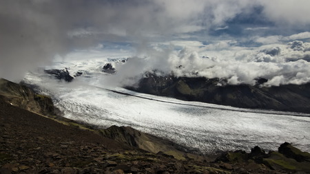 Skaftafellsjokull glacier "flowing" diagonally across photo with clouds above the glacier and mountains in background in Skaftafell National Park, Southern Iceland.の写真素材