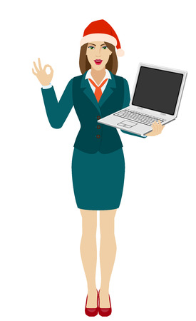Businesswoman in Santa hat holding a laptop notebook and show a okay hand sign. Full length portrait of businesswoman in a flat style. Vector illustration.のイラスト素材