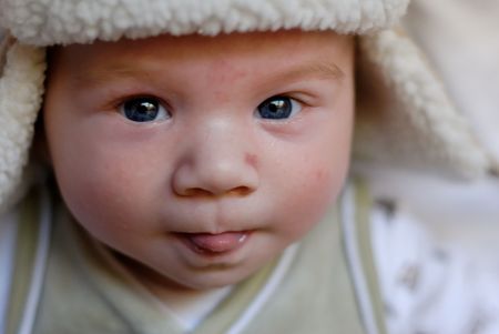Cute baby boy in a hat showing his tongueの写真素材