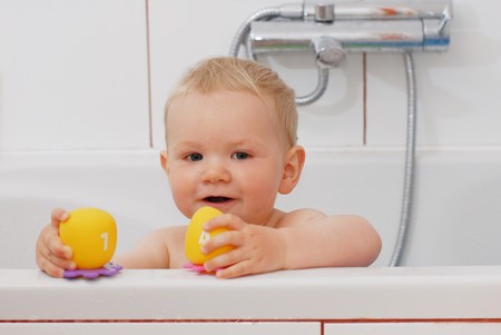 Adorable baby boy playing with toys while bathingの写真素材