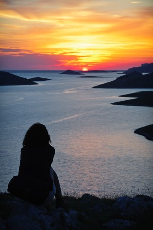 Silhouette of a woman watching golden sunset over seaの写真素材