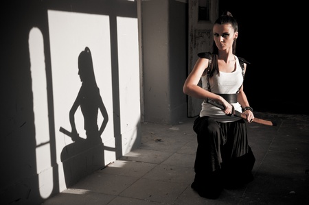 Beautiful woman unsheating sword with shadow showing her figureの写真素材