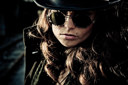 Face of mystery brunette woman wearing dark glasses and a hat, dark closeup outdoor portrait.の写真素材