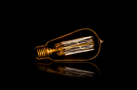 Edison bulb on a reflective surfaceの写真素材