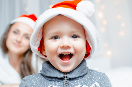 The child is happy, laughs on the background lights behind the mother looks at him