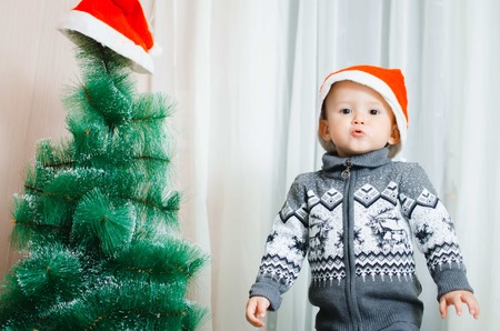 Child standing near Christmas tree surprised happy soon new year and Christmasの写真素材
