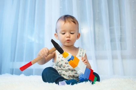 The child is sitting on the bed with a hammer and bet the designerの写真素材