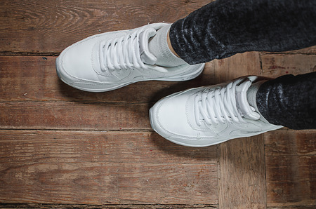 sneakers and feet on the wooden floor, women's athletic shoesの写真素材