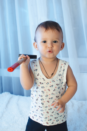 The child sits with a hammer and a screw looking at their toolsの写真素材