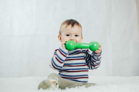 The child is involved in sports, fitness lifting dumbbell
