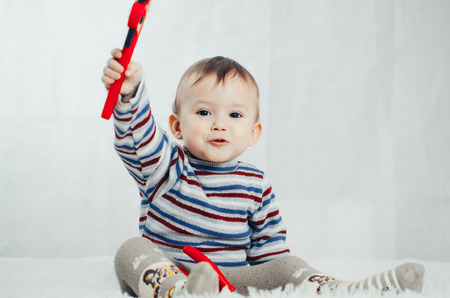 The child sits and shows a red wrench on an isolated background