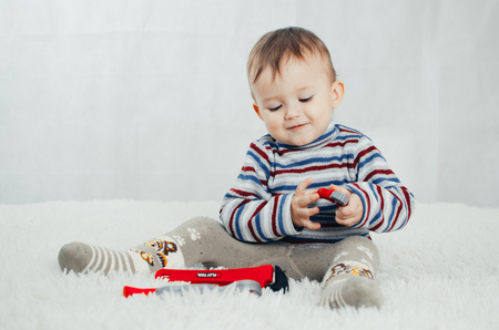 The child sits and shows a red pliers on an isolated backgroundの写真素材