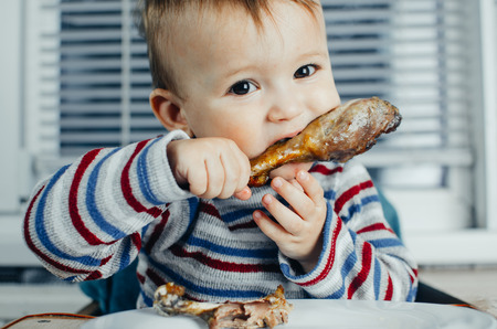 The child greedily eating chicken, fatty and delicious in the kitchen, very hungryの写真素材