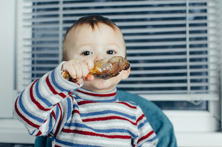 The child greedily eating chicken, fatty and delicious in the kitchen, very hungryの写真素材
