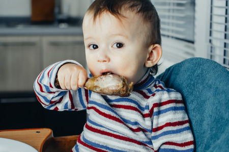 The child greedily eating chicken, fatty and delicious in the kitchen, very hungryの写真素材