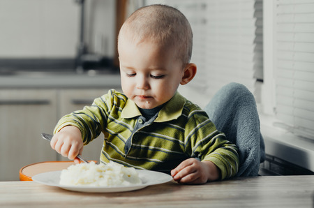 The child eats mashed potatoesの写真素材