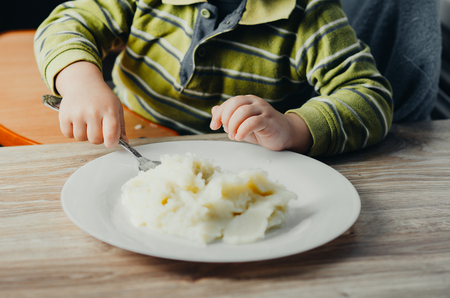 The child eats mashed potatoesの写真素材