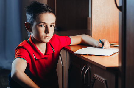 The child late at night writing in a notebook, doing homework,set goalsの写真素材