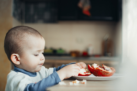 Baby eats a pomegranate, ripe and juicy, very tasty and joyfullyの写真素材